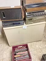 Front view: cabinet, stacked stereo components, speaker, milk crate of records