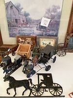 Group shot of various metal, cast iron and wooden horse & buggy models and decor