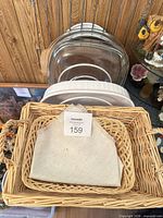 Front view showing wicker basket, cloth liner, round wicker trivet, glass domes and white dish stacked