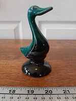 Front left view of drip-glazed ceramic duck on base beside ruler
