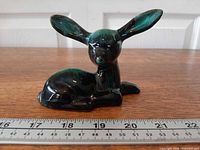 Full view of reclining fawn figurine with ruler for scale (~11 cm)