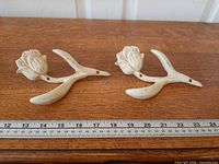 Two cast iron tulip wall hooks on table with ruler