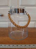 Front view showing glass body, metal collar, jute handle