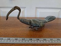 Left side view of entire ibis sculpture beside ruler