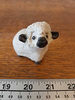 front angled view of sheep figurine beside ruler for scale