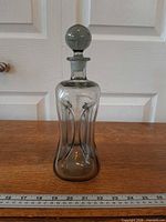 Front view of smoked grey Kluk Kluk decanter with stopper, ruler for scale