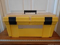 Front view of yellow toolbox with black latches and handle visible