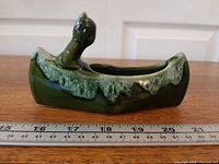 side view showing entire canoe planter and figure with ruler for scale