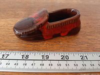 Side profile of ceramic moccasin shoe with ruler indicating length