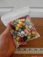 Sealed bag of assorted color cord locks held next to ruler