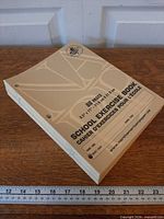 Stack of eight beige exercise books showing front cover layout and three-hole punches