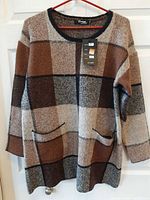 Full front view of sweater showing plaid pattern, pockets and tag