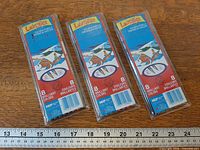 Front view of three sealed Laurentien pencil sets on table with ruler for scale
