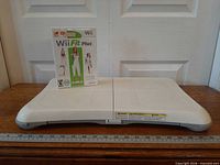 Wii Balance Board with Wii Fit Plus game case, front view