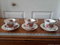 Three Royal Albert Centennial Rose teacup and saucer sets lined up