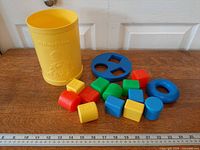 Overall view of container, lid and shape blocks displayed on surface