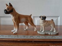 Boxer and pug figurines side by side with ruler for scale