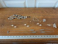 Group overview of all six jewelry pieces on table with ruler for scale