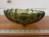Side profile showing olive green glass, ruffled edge and one of three feet