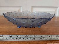 Side profile showing hobnail texture, blue tint, three feet, ruler for scale