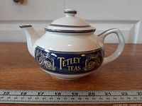 Left profile of Tetley Teas teapot showing logo and ruler for length
