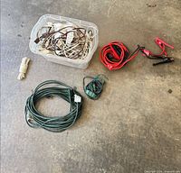 Overall lot showing extension cord, jumper cables, pigtail cord, white cord, and bin of assorted cords