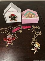 Overview showing two necklaces with character pendants and boxed gingerbread brooch