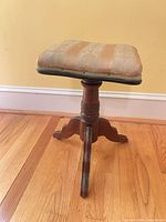 front view of adjustable piano stool showing upholstery and turned pedestal