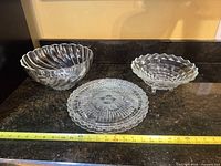 Three clear glass pieces on countertop with tape measure showing scale