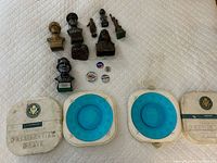 Group shot of all items: three plates in cases, eight busts/figures, four buttons