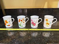 Front view of all four mugs showing designs and words