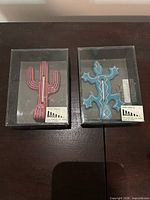 Both boxed wall hooks, cactus and lizard designs visible
