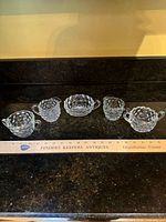 Five Fostoria American crystal creamers lined up with ruler for scale