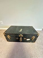 Closed trunk front view showing brass latches, lock, corner guards