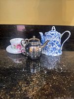 Group showing teacup, saucer, blue floral teapot and silver-plated teapot
