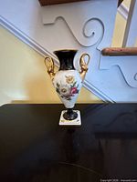 Front view showing floral decoration, gold handles and square base