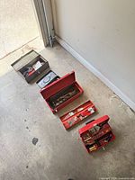 Four metal toolboxes opened on garage floor