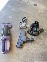 Vacuum body with accessories laid out: motorized brush, floor nozzle, charging dock