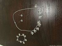 Full view of necklace, bracelet, and earrings laid flat showing overall design and quantity