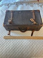Top view showing entire suitcase, leather texture, strap and latch closures, ruler for scale