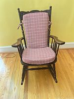 front view of carved wooden rocking chair with plaid cushions