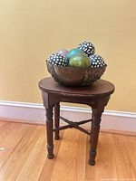 Full view of wooden stool with decorative bowl on top