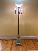 Full view of floor lamp illuminated showing shade, arms, base
