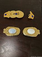 Front view of all four pieces: two rectangular buckle halves with white cabochons, elongated clip with blue cabochon, small triangular clip with blue cabochon