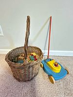 Basket of wooden blocks beside push toy mower