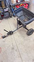 Full view of Agri-Fab tow-behind spreader showing hopper, wheels, hitch bar
