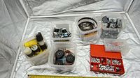 overall view of six clear tubs and one red box containing rollers, clamps, plugs, fasteners, brackets and inserts