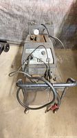Front view of welder on cart with torch, cables, regulator and gauge visible