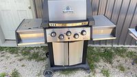 Full front view of Broil King Sovereign grill showing four control knobs, side shelves, wheels