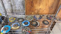 Shelf with 13 assorted abrasive discs showing overall quantity and condition